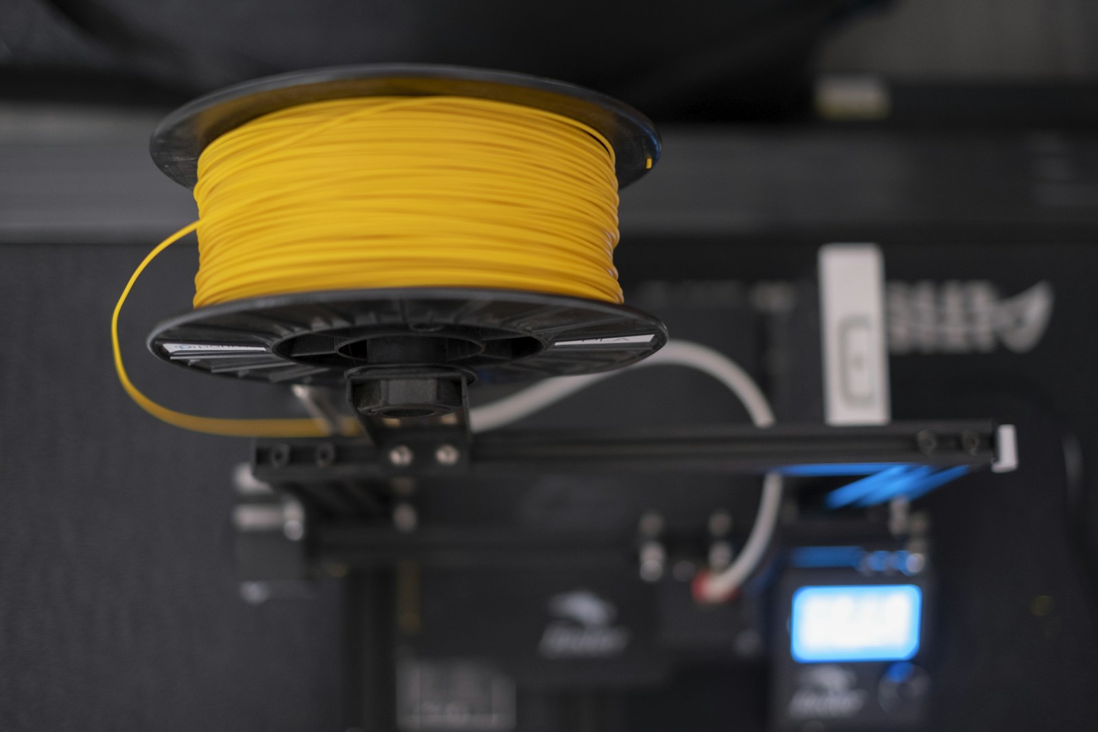 3D printer bench with freshly printed parts and a filament spool: 3D part production cost